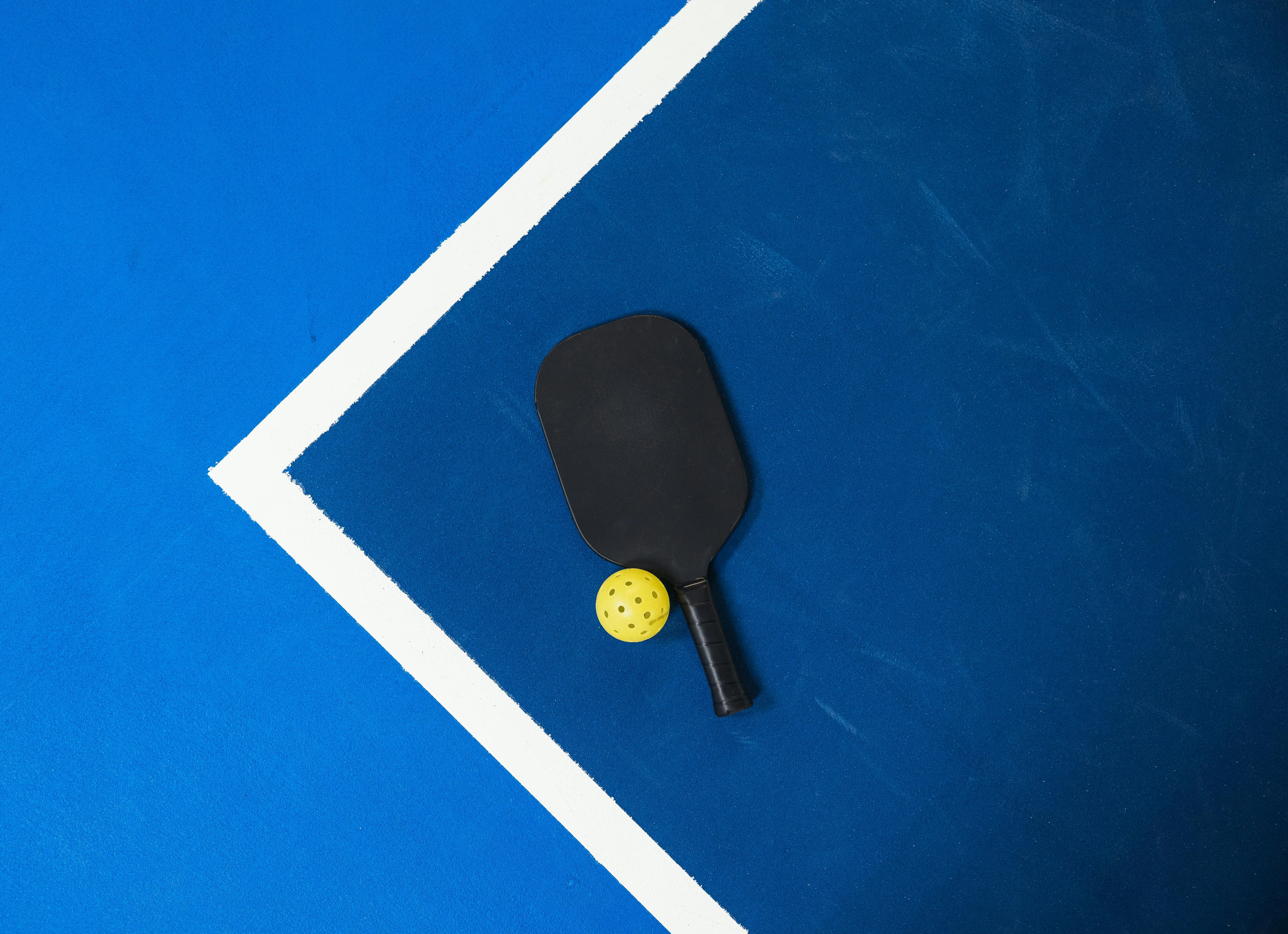 Professional pickleball paddle and ball on a blue court in Hong Kong